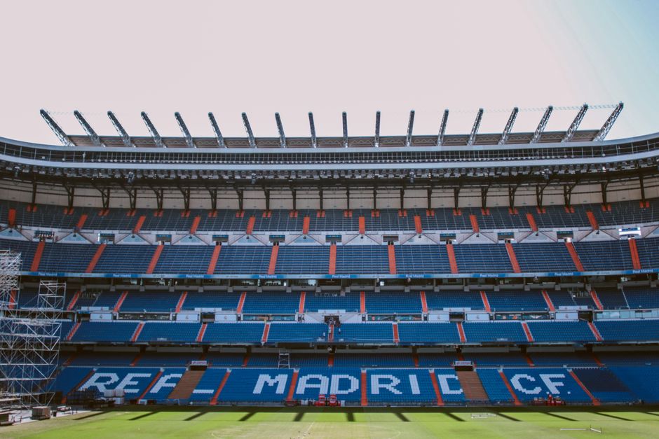 Campo de fútbol rodeado de gradas vacías bajo un cielo parcialmente nublado