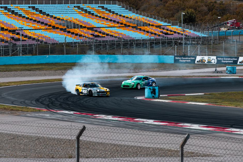 Coches derrapando a alta velocidad en curva, envueltos en nube de humo